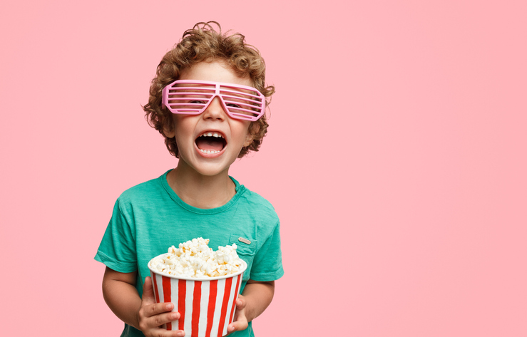 Screaming boy in glasses holding popcorn