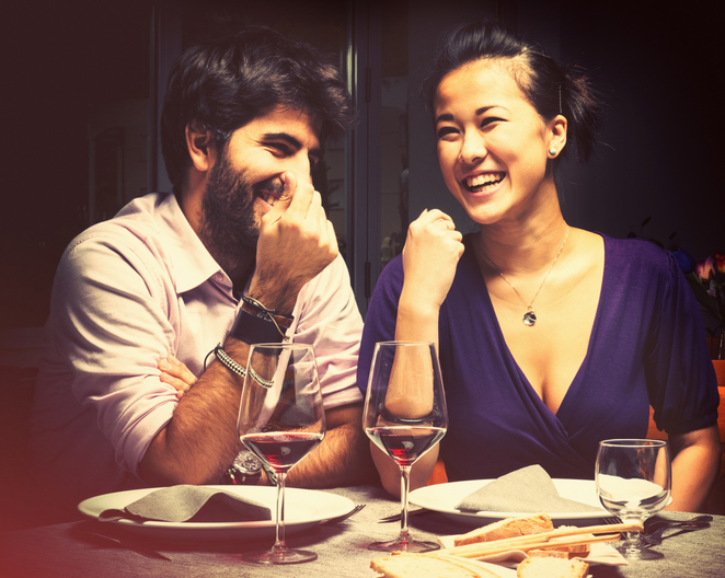 A couple laughing together while eating and drinking